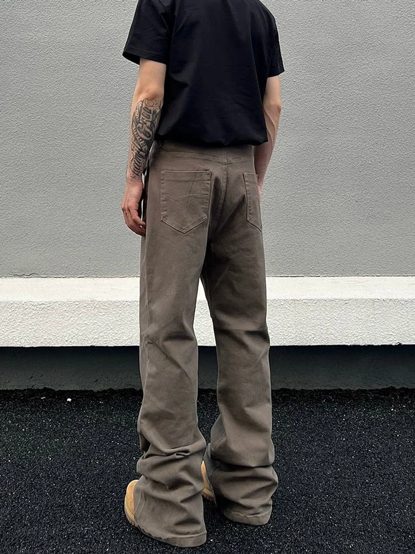 Rear full-body view of loose taupe washed straight-leg jeans showing classic back patch pockets and boot-covering hem