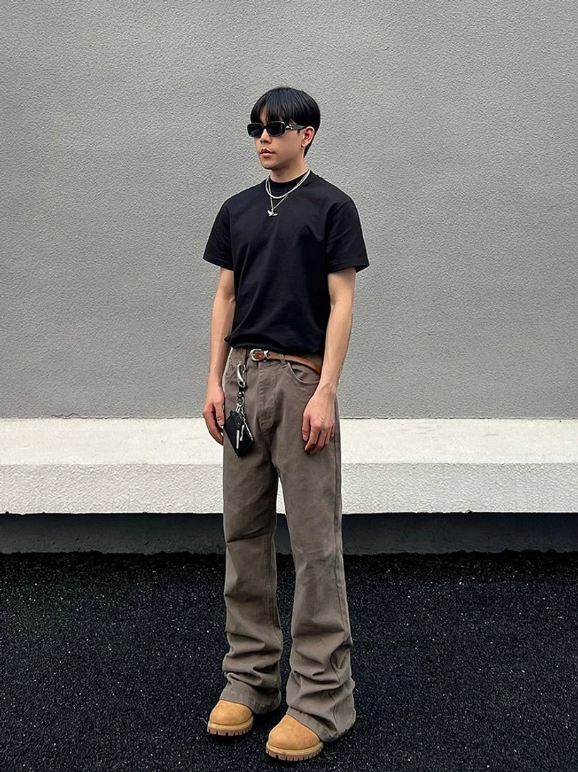 Front styled view of taupe washed wide straight-leg denim jeans with hanging waist chain and suede work boots