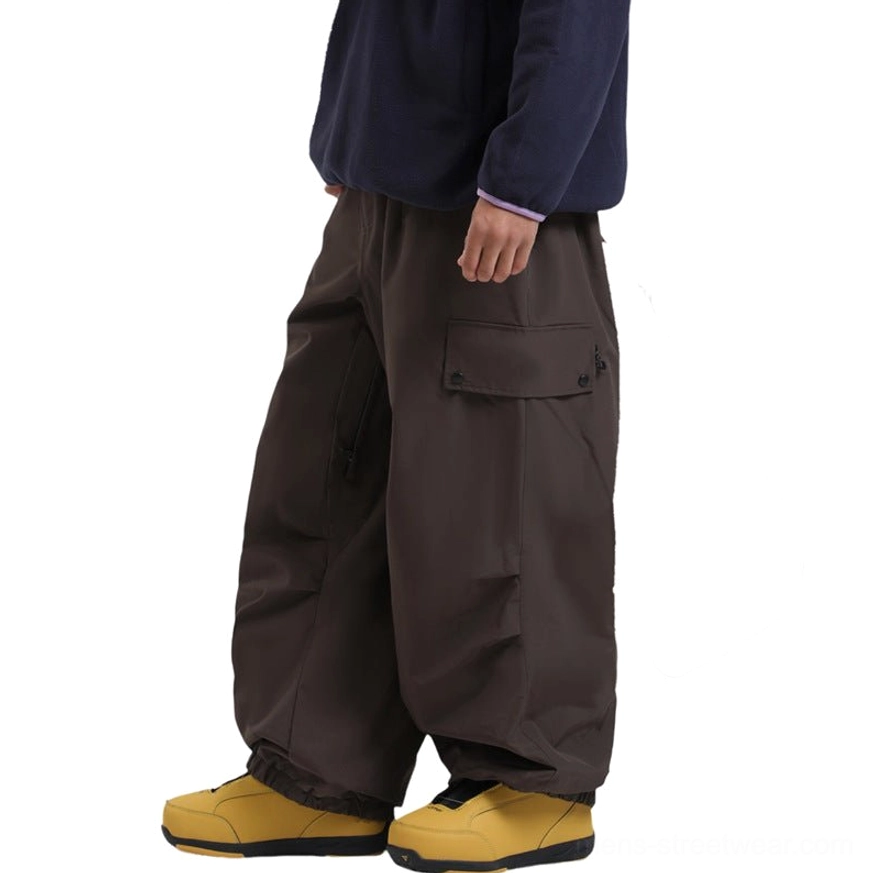 Technical wide-leg cargo snow pants with relaxed fit, multiple utility pockets, reinforced lower legs, inner-thigh ventilation, and built-in snow gaiters