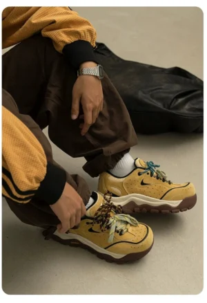 Yellow brown chunky trail sneakers styled with brown trousers and a yellow sweater, highlighting the cushioned platform sole and patterned laces