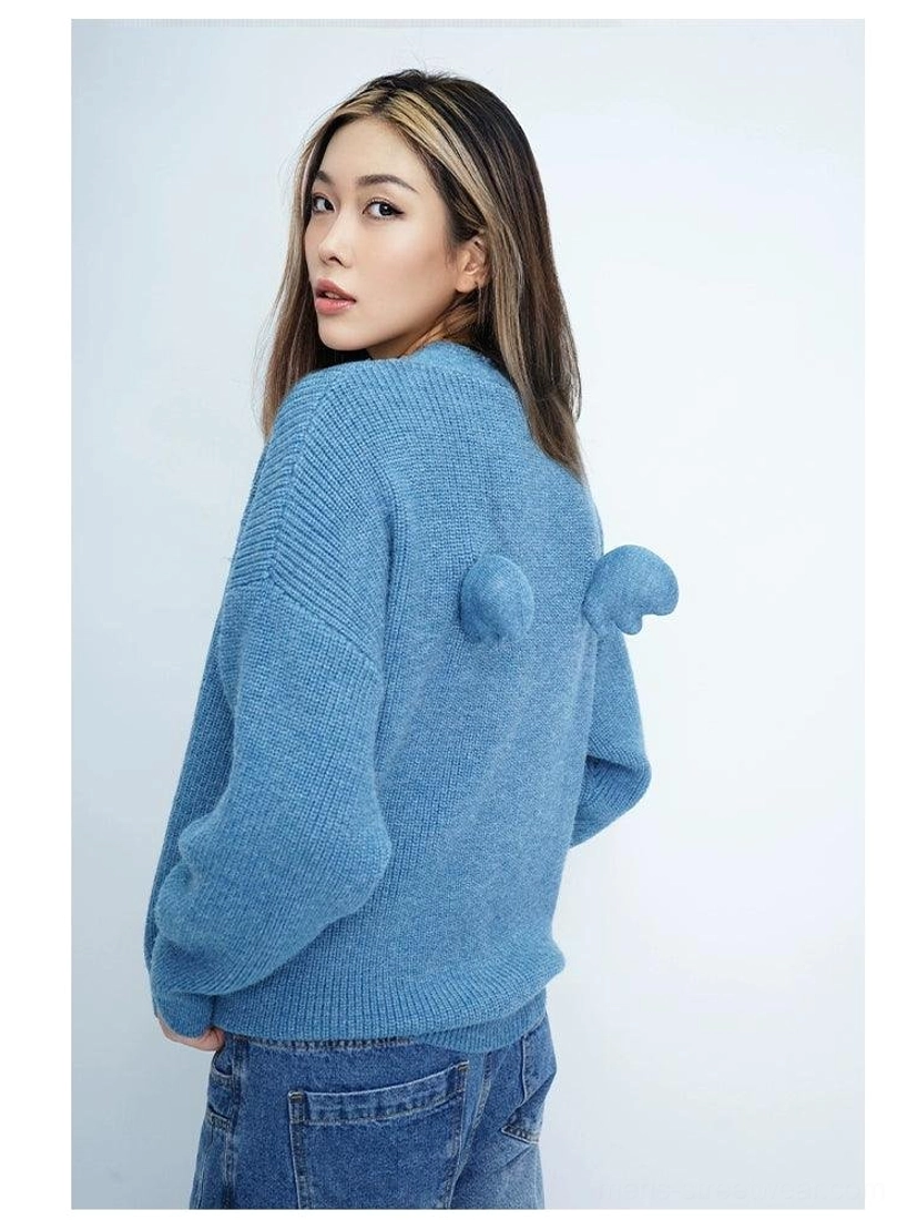Textured oversized knit cardigan with soft fuzzy finish, long sleeves, relaxed fit, and artistic wing pom-pom detailing