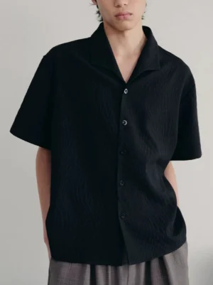 Black textured quilted camp collar shirt on male model showing relaxed Korean streetwear fit and wavy jacquard fabric