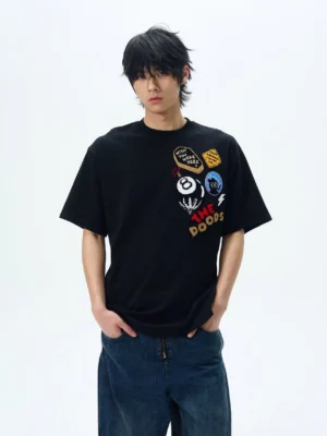 Black THE DOODS graphic patch oversized streetwear T-shirt styled with dark blue wide-leg jeans
