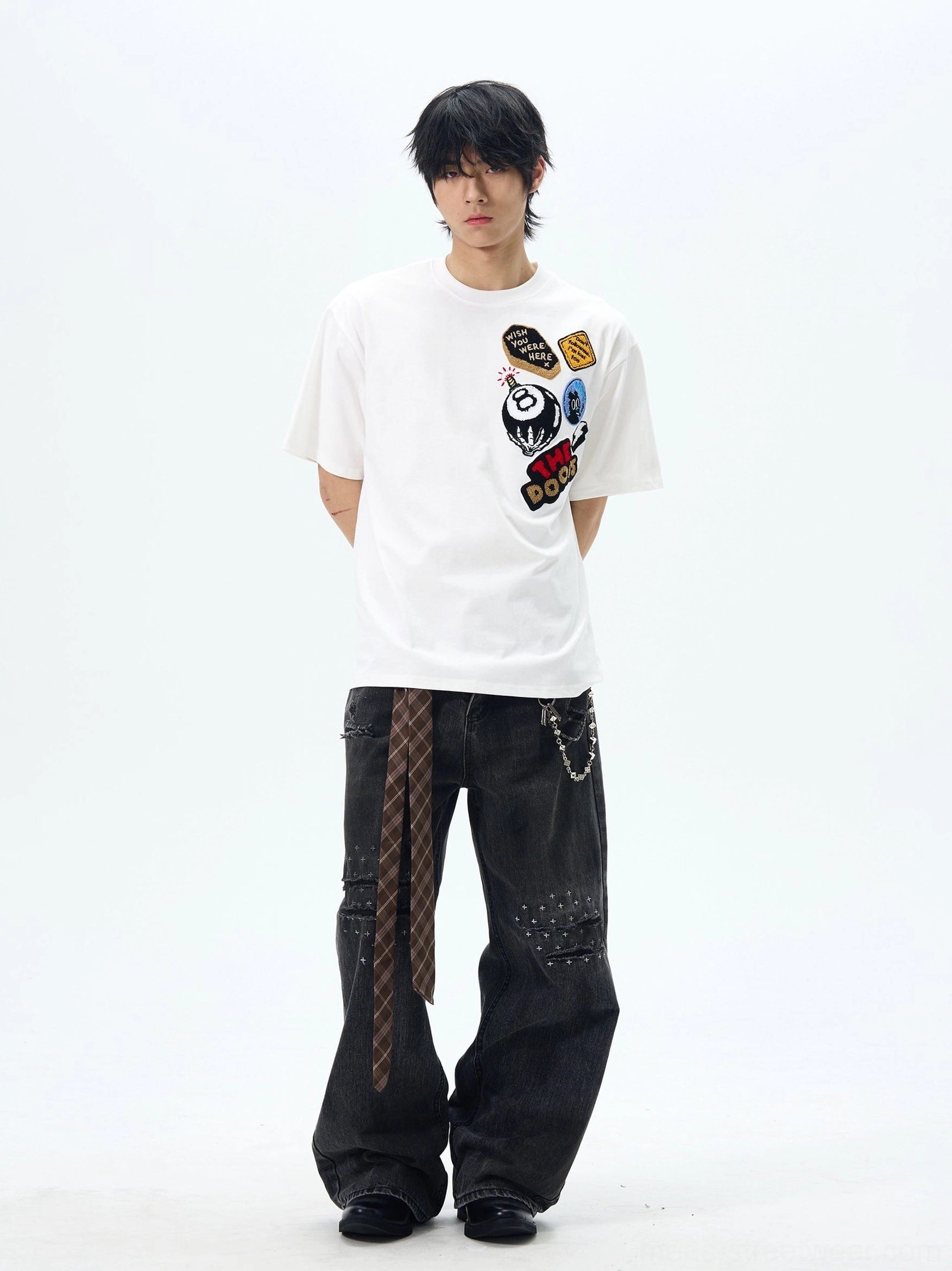 White THE DOODS embroidered graphic patch short sleeve streetwear T-shirt with distressed black wide-leg jeans