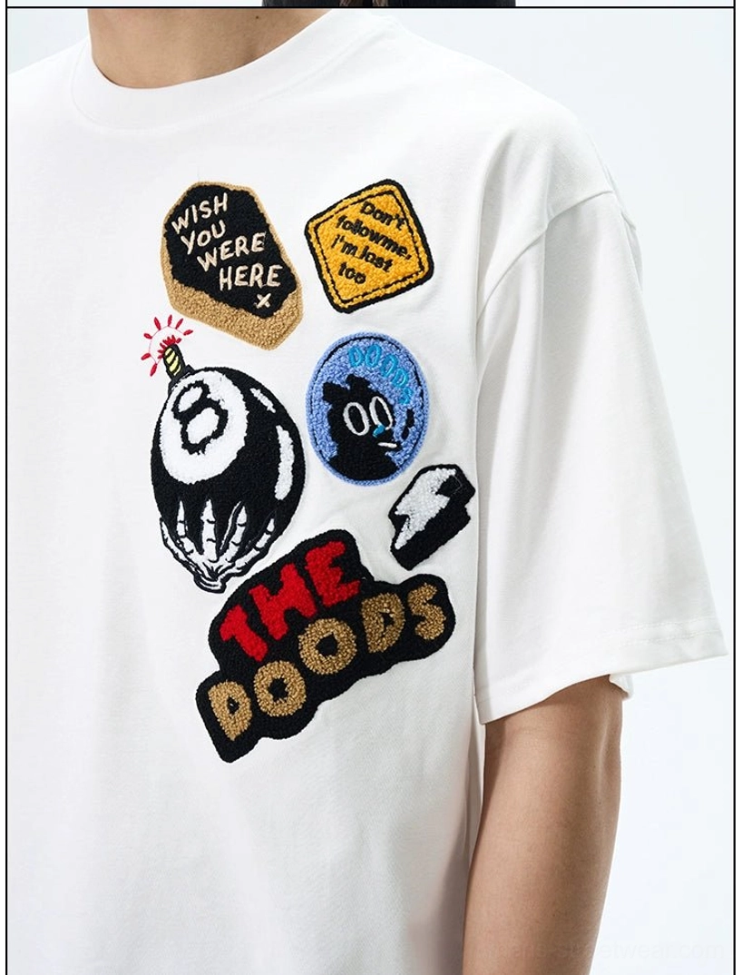 Close-up of THE DOODS white graphic patch T-shirt showing WISH YOU WERE HERE badge, 8-ball, and embroidered logo