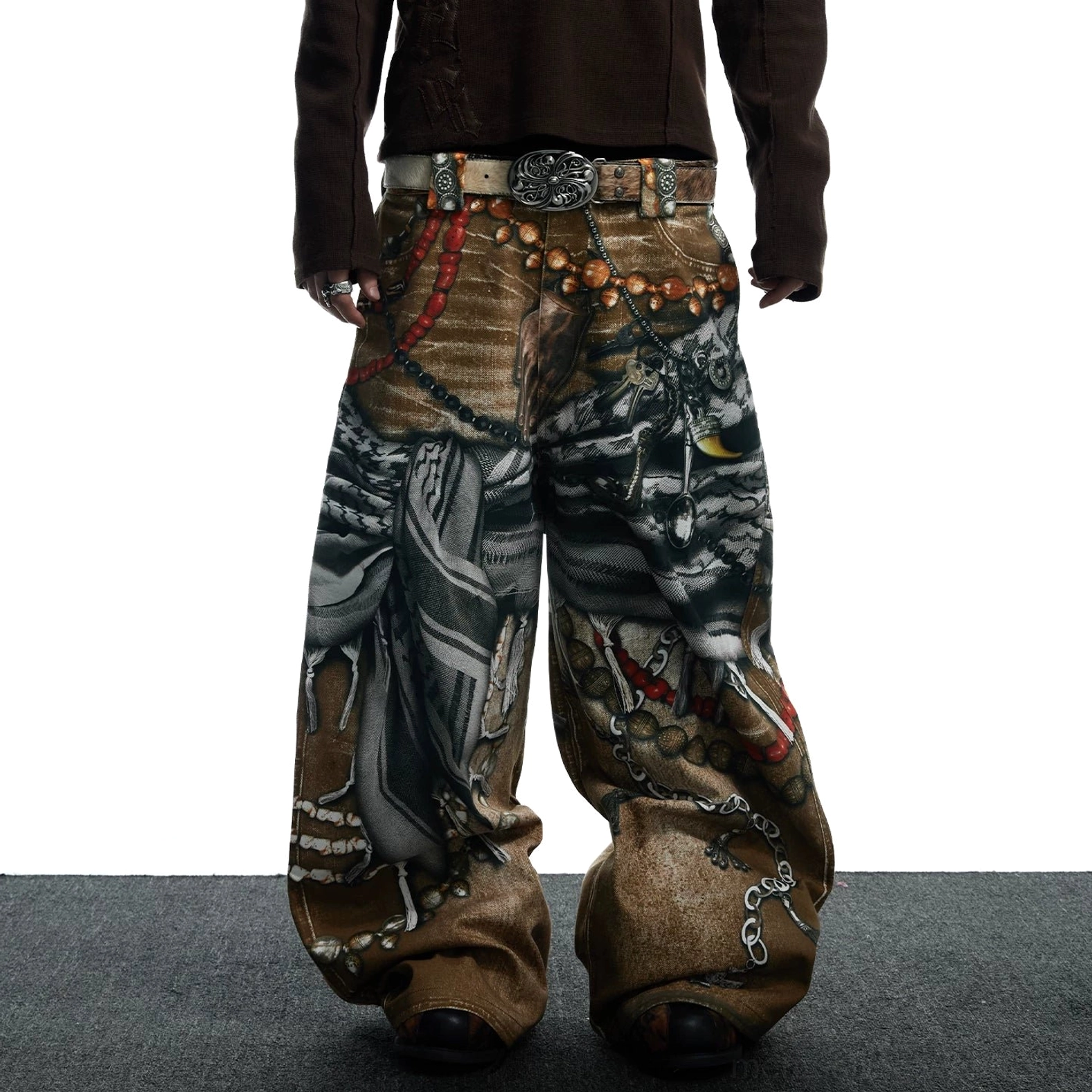 Front static view of tribal collage print wide-leg jeans with layered vintage chain and bead graphics styled with a dark brown long-sleeve top