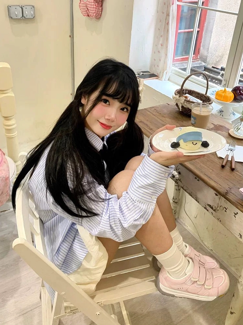 Pink triple strap sneakers worn with a striped blouse and shorts in a casual everyday fashion look