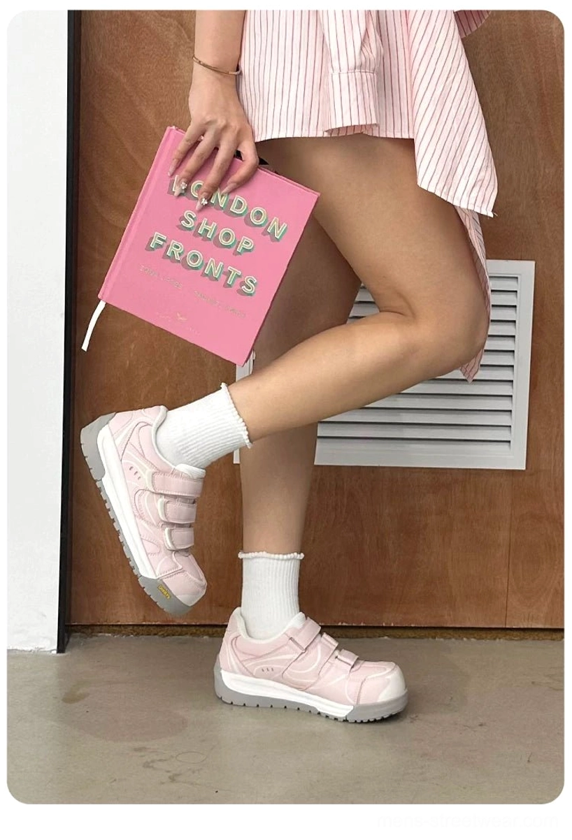 Low-angle view of pink triple strap platform sneakers styled with a striped skirt and white socks