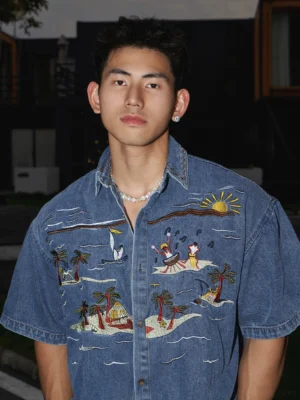 Short sleeve tropical embroidered denim shirt in washed indigo blue with palm tree sunset artwork and relaxed Korean streetwear fit