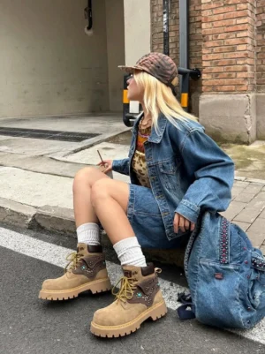 Female model styling turquoise embellished tan ankle boots with denim streetwear outfit and knit beanie outdoors