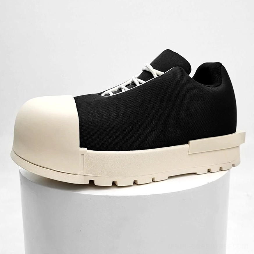 Two-tone black canvas platform sneakers displayed on a white pedestal with oversized cream toe, lug sole, and contrast laces