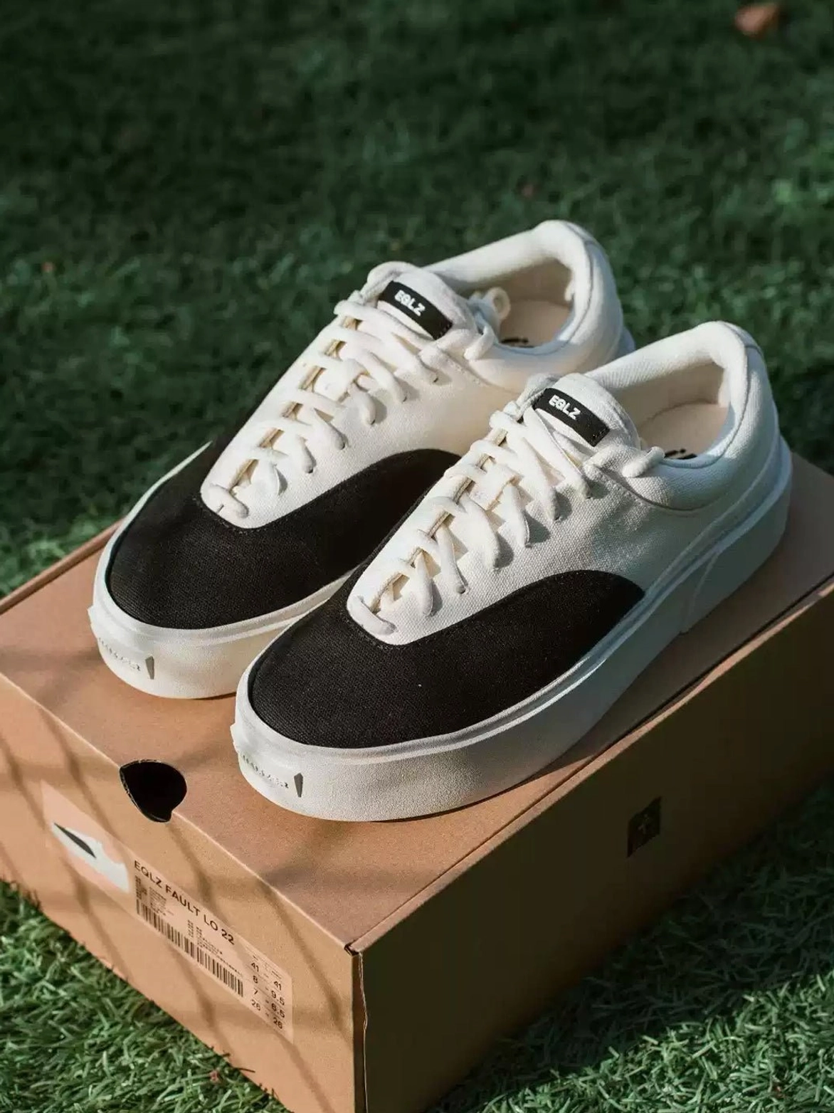 Pair of two-tone canvas platform skate shoes displayed on a shipping box showing the black and egret white color block design