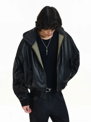 Black hooded faux leather bomber jacket shown from a front lower three-quarter view with matte shell, army green lining, ribbed cuffs, and cropped streetwear fit