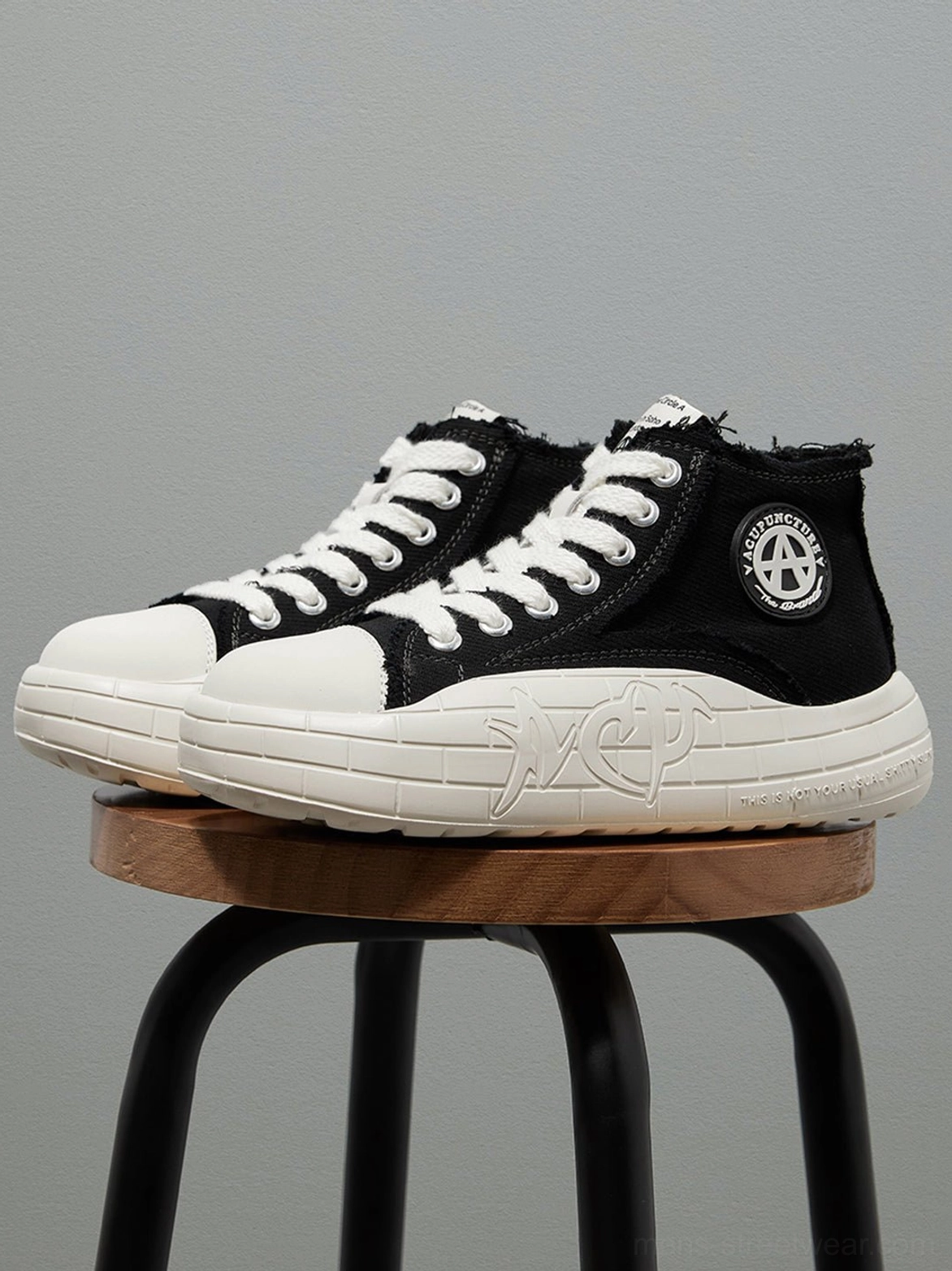 Angled product view of black and white canvas high-top platform sneakers with textured thick sole and frayed collar