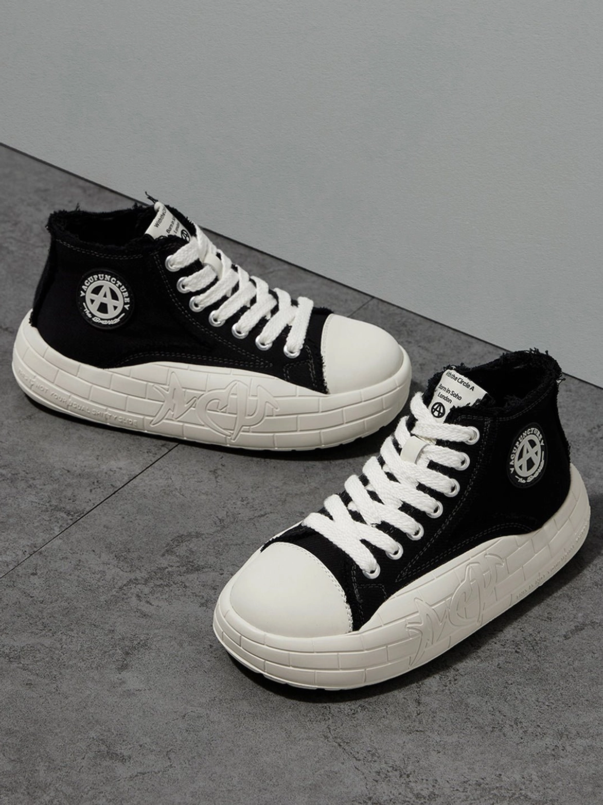 Black and white platform canvas high-top sneakers showing the side profile, laces, and upper details