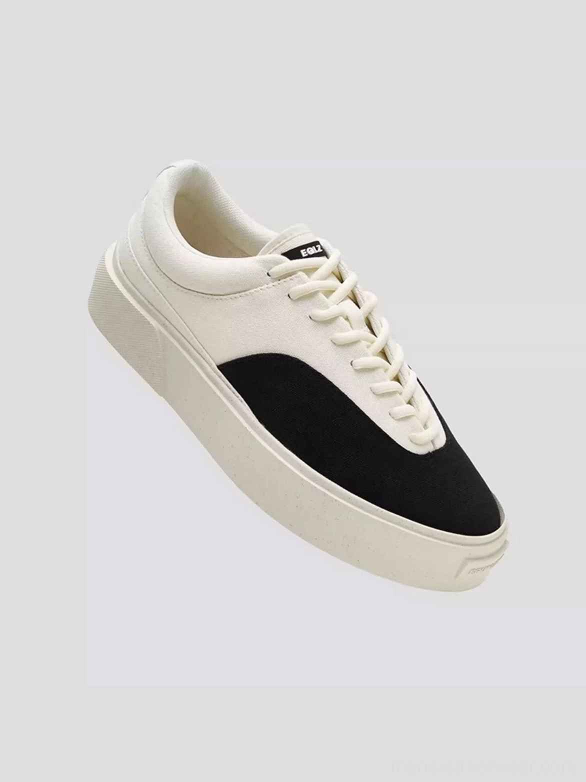 Low-angle detail view of two-tone canvas skate shoes with substantial platform rubber sole, rounded toe, and lace-up front