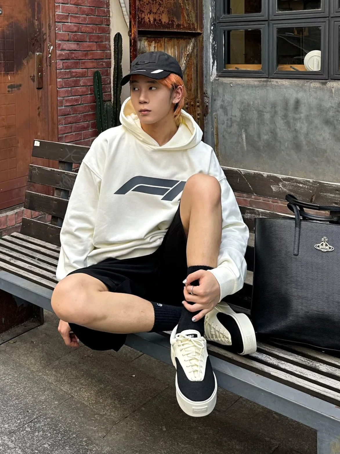 Young man wearing two-tone platform canvas skate shoes with casual Seoul-inspired streetwear beside an urban brick wall