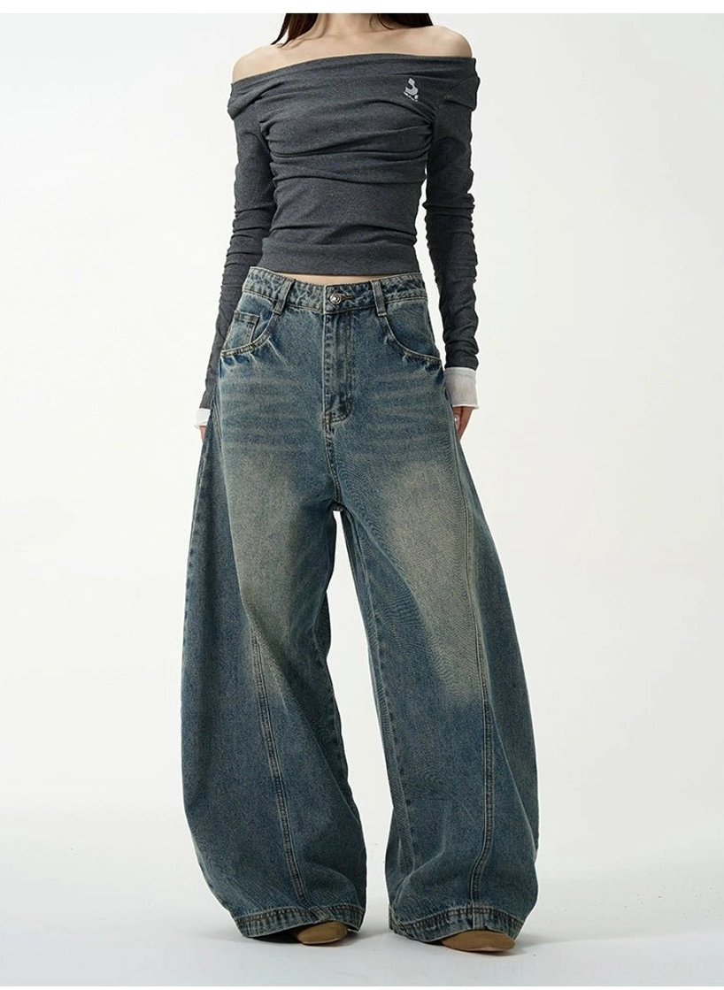 Female model wearing high-volume vintage blue ultra wide-leg balloon jeans with a gray long-sleeve top