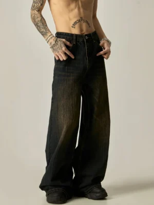 Front low-angle view of ultra-wide leg dark wash denim jeans with vintage brown faded wash, high waistband, and oversized streetwear silhouette