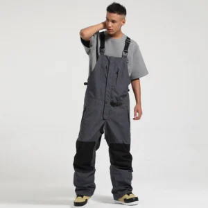 Unisex dark gray bib snow pants with black knee reinforcement, chest utility pocket, adjustable waist buckles, and relaxed techwear fit