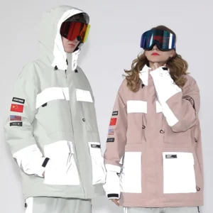Unisex reflective color block ski jackets in white and pink worn by two models with ski goggles in a winter streetwear studio look