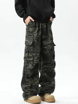 Front low-angle view of unisex military green camouflage wide-leg cargo pants with oversized flap pockets and stacked tan work boots