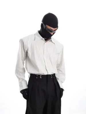 Front full-body view of a relaxed vertical stripe Oxford shirt styled with black wide-leg trousers and tactical streetwear accessories