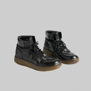 Front three-quarter view of vintage black genuine horsehide leather high-top sneakers with distressed finish, metal lace fasteners, padded ankle collar, and gum-brown rubber outsole