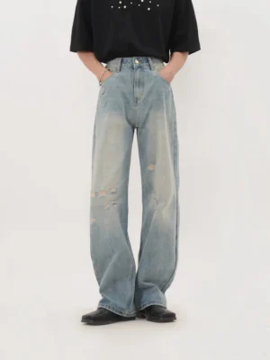 Male model wearing vintage blue distressed wide-leg jeans with ripped thighs and knees, styled with a black streetwear T-shirt