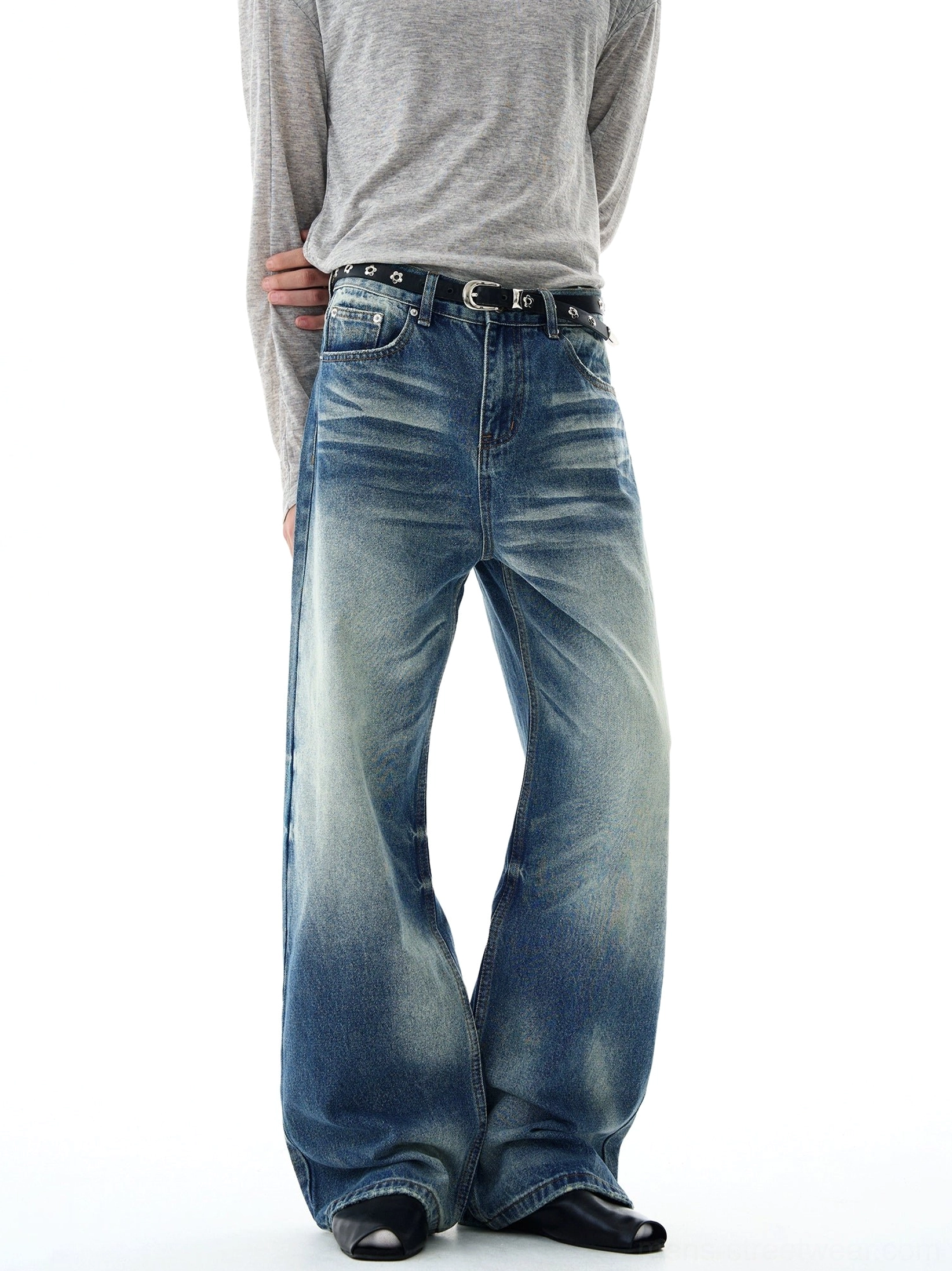 Three-quarter side view of vintage washed blue flare-leg jeans with asymmetric fading, clean topstitching, relaxed thigh, and dramatic wide hem