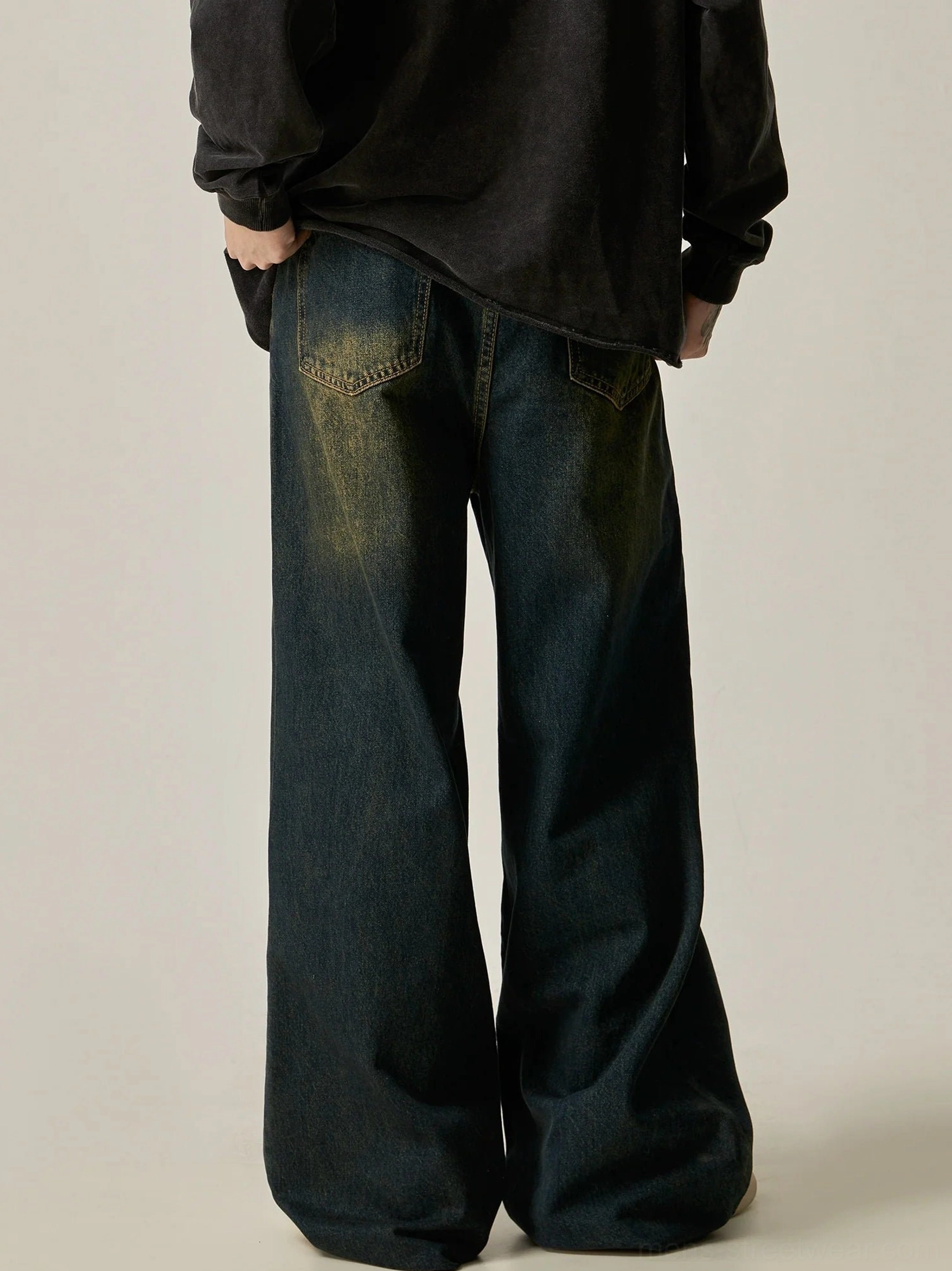 Rear view of vintage blue ultra-wide leg jeans showing faded back pockets and washed denim details with an oversized black top