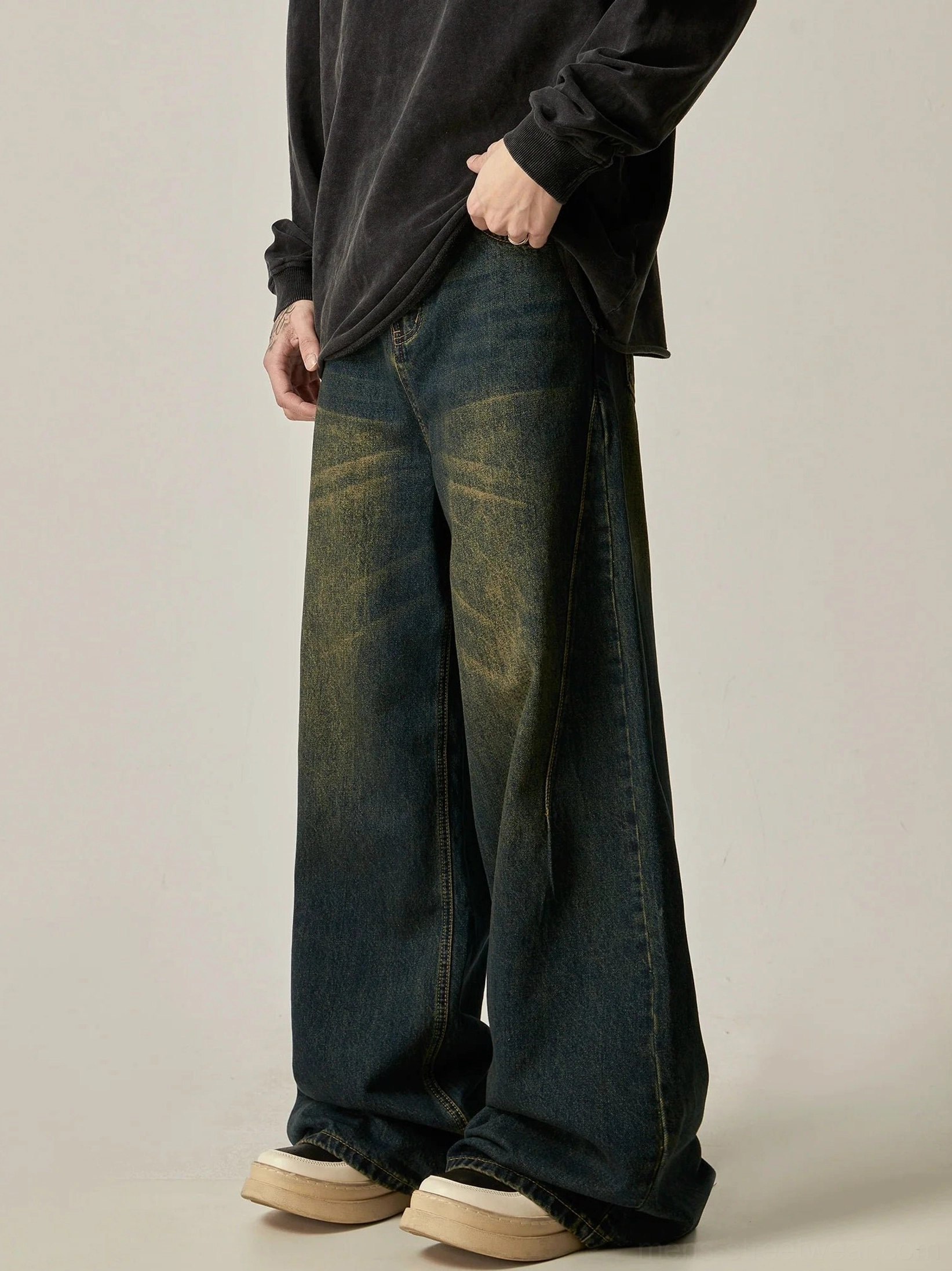 Side front view of vintage blue wide-leg jeans with relaxed loose fit, detailed seams, oversized black top, and platform shoes