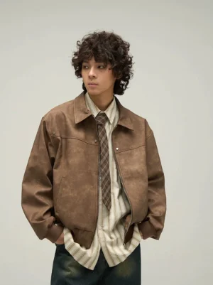 Front view of a vintage brown faux leather bomber jacket with oversized drop shoulders, metal front details, and ribbed waistband