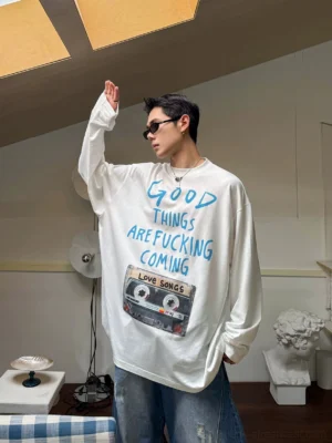 Front view of white vintage cassette graphic oversized long sleeve tee with blue handwritten slogan print and dropped shoulders