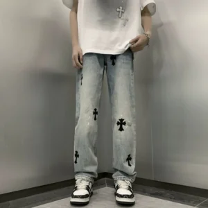 Front view of light blue vintage cross patch wide leg denim jeans with black appliques, paint splatter details, loose streetwear fit, white oversized tee, and sneakers