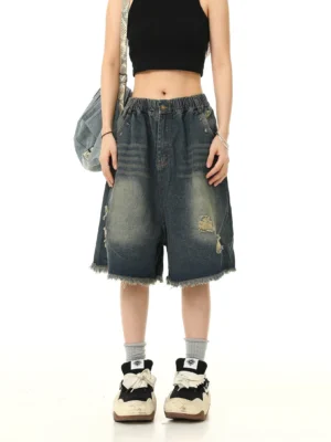 Front view of loose fit distressed denim Bermuda shorts with elastic waistband, ripped details and frayed raw hem