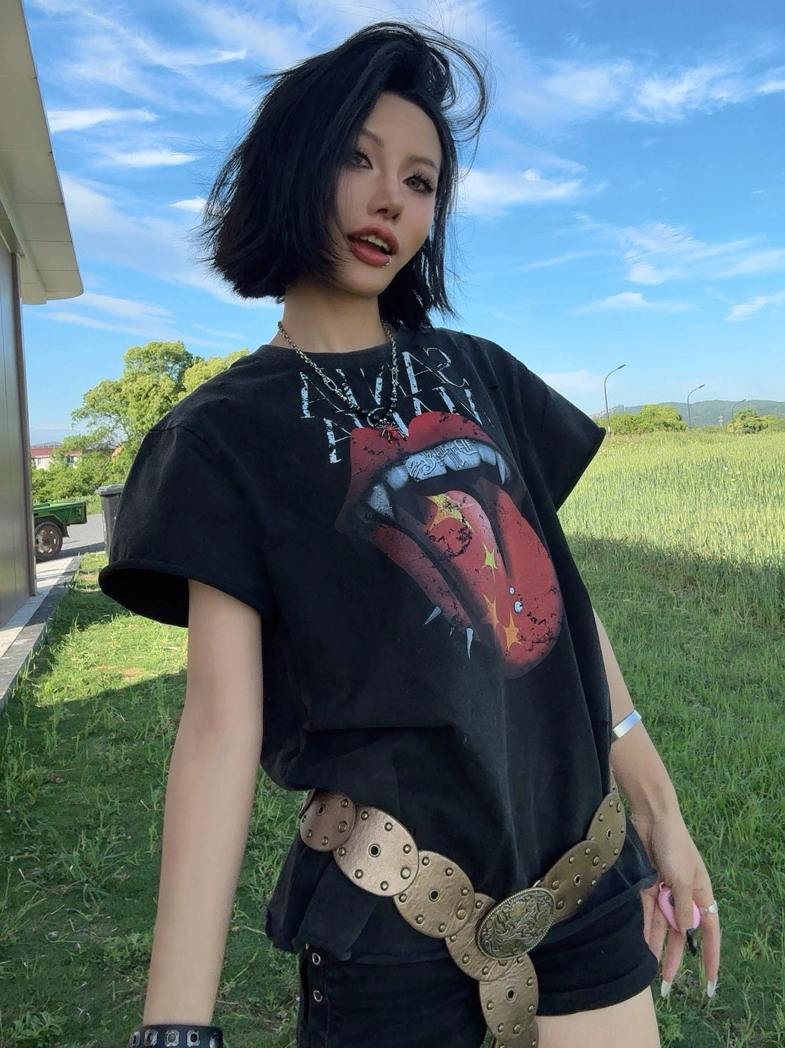 Vintage faded black rock graphic tee with vampire tongue print styled with wide belt and alternative fashion outfit