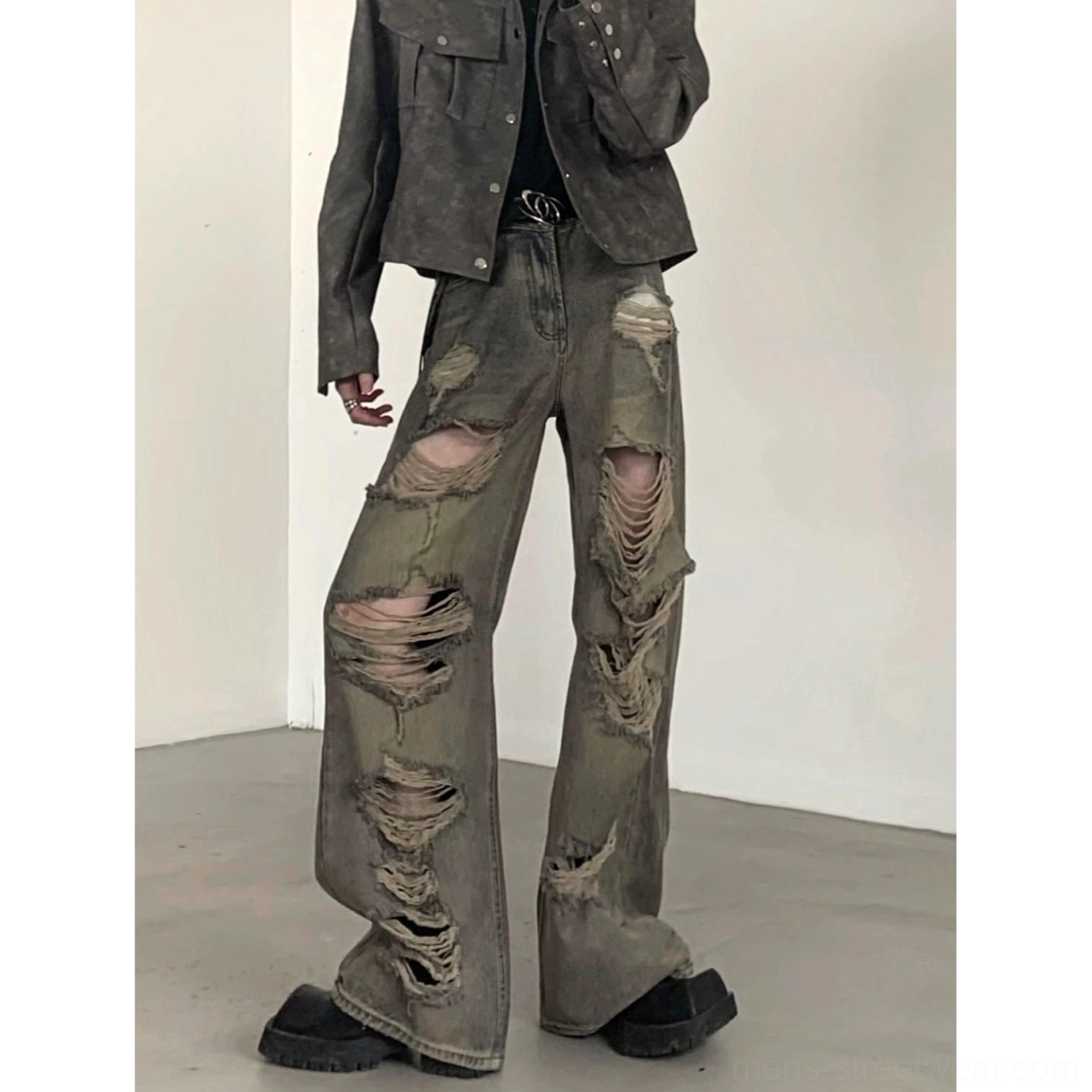 Low-angle front view of vintage faded distressed wide-leg denim cargo pants with layered frayed rips and raw hems