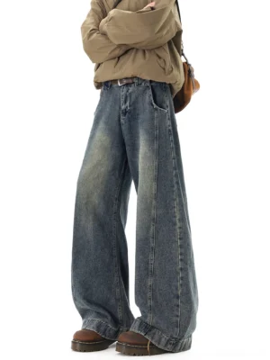 Vintage faded indigo ultra-wide streetwear jeans front three-quarter view styled with khaki jacket brown platform boots and crossbody bag