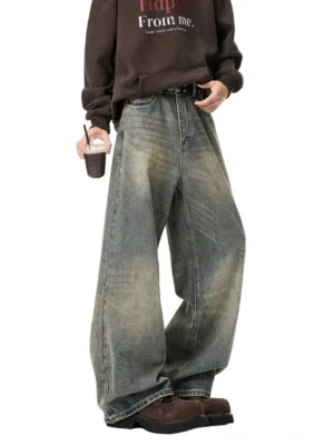 Vintage faded wide-leg jeans front view with relaxed stacked hem, brown graphic sweatshirt, belt, and chunky work boots
