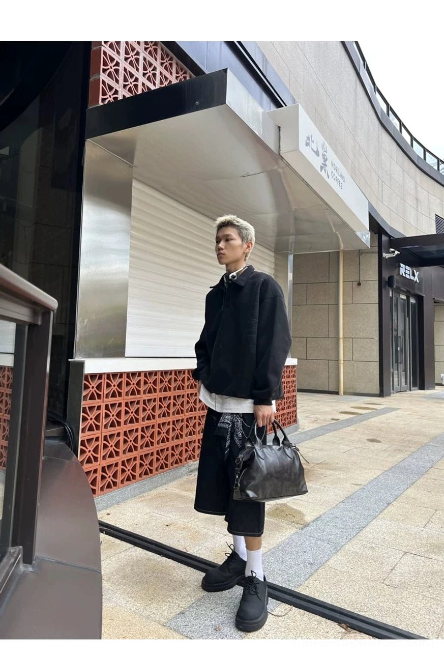 Male model carrying a vintage faux leather compact weekender bag by the top handles on a city street