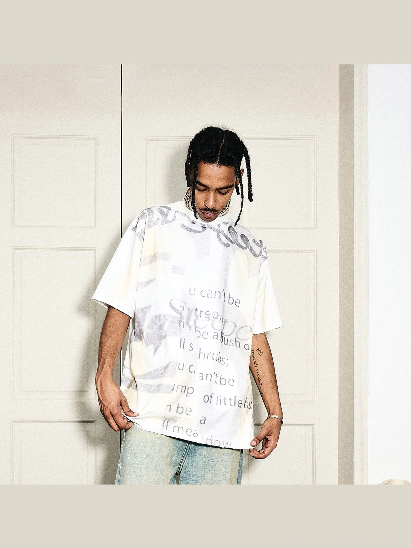 Front view of a cream faded oversized graphic text T-shirt with gray graffiti lettering and relaxed Korean streetwear fit
