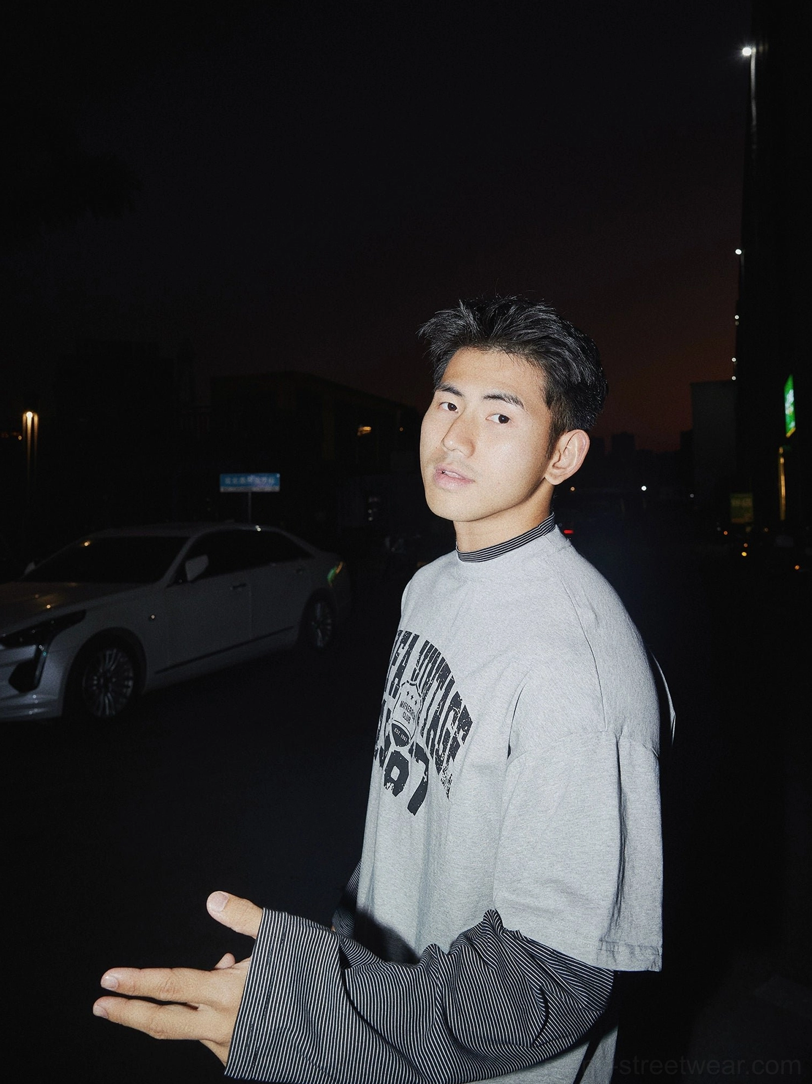 Side view of oversized vintage graphic layered crewneck tee with striped contrast sleeves and retro streetwear styling