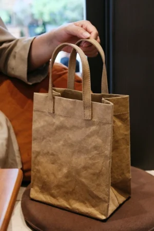 Khaki vintage kraft paper texture cotton tote bag displayed on a round stool with soft double handles