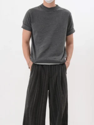 Dark gray mock layered knit short sleeve T-shirt with rolled cuffs and contrast hem styled with striped wide leg pants in a Korean streetwear studio outfit