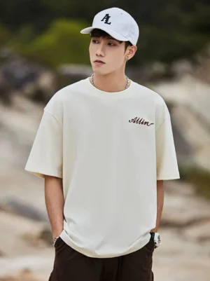 Ivory white oversized streetwear T-shirt front view with small cursive chest graphic and relaxed casual fit