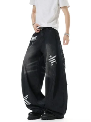 Male model wearing vintage washed black ultra baggy balloon jeans with striped star patch appliques in a white studio