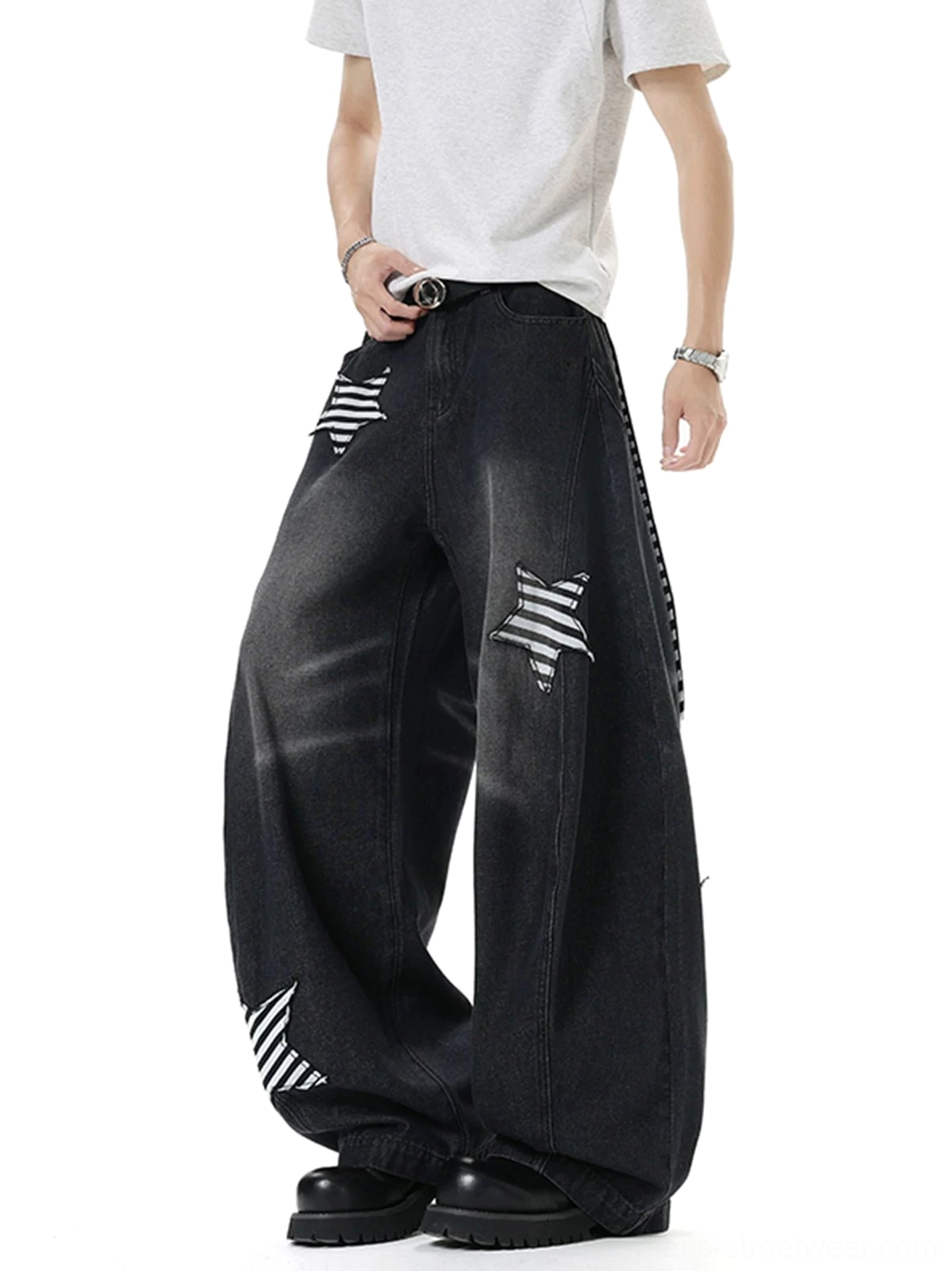 Male model wearing vintage washed black ultra baggy balloon jeans with striped star patch appliques in a white studio