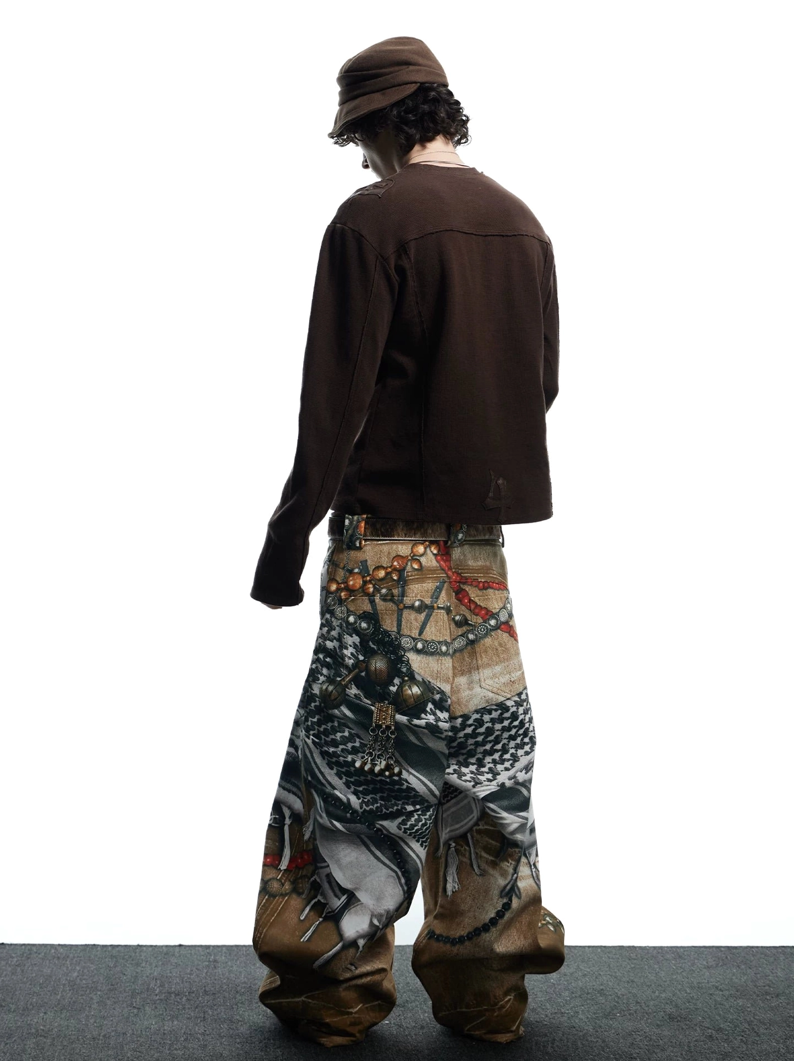 Rear full-body view of vintage tribal collage print jeans showing the waistband, relaxed wide-leg shape, and detailed back artwork