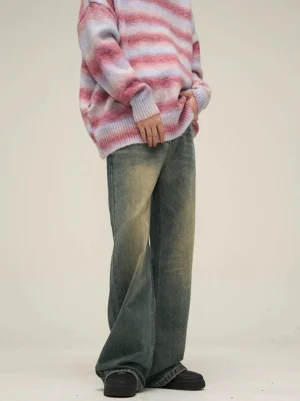 Vintage wash wide-leg jeans styled with a gradient pink striped oversized knit sweater and black casual shoes in a low-angle streetwear outfit